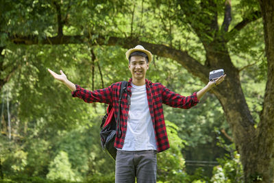 Full length of young man using mobile phone in forest