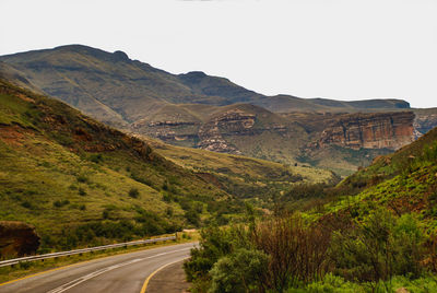 Road leading towards mountains against clear sky