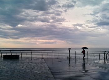 Man standing on pier over sea against sky