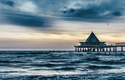 Scenic view of sea against cloudy sky at sunset