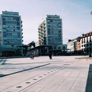 People on city street by buildings against sky