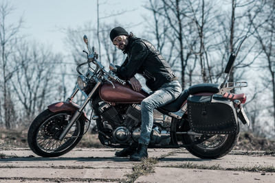 Mid adult man sitting on motorcycle in forest