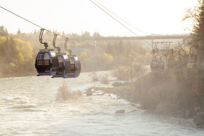 Overhead cable car over river against sky