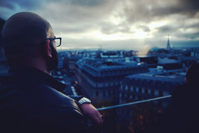 Portrait of man with cityscape against sky at dusk