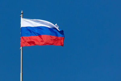 Low angle view of flag against blue sky