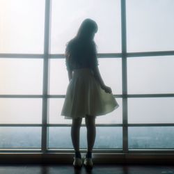 Full length of young woman standing by railing