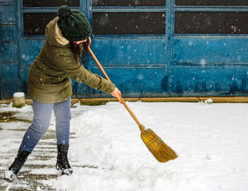 A woman cleaning the snow in the backyard