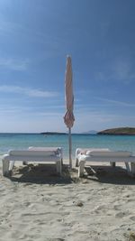 Deck chairs on beach against sky