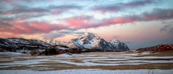 Snow covered landscape against sky during sunset