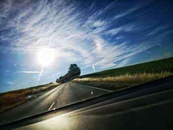 Road against sky seen through car windshield