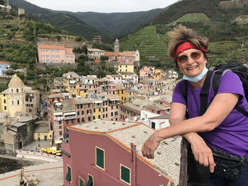 Senior woman looking townscape of italian town from the fortress walls - vernazza, cinque terre