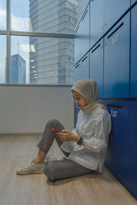 Side view of woman sitting on wooden floor