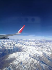 Airplane flying over snowcapped mountains against sky