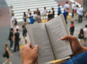 Cropped hand holding open book