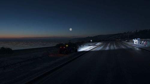 Road amidst illuminated city against sky at night