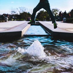 Low section of man jumping over fountain