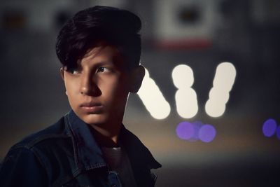 Thoughtful teenage boy looking away in city at night