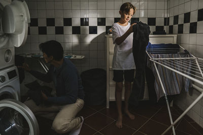 Father and son in utility room doing laundry