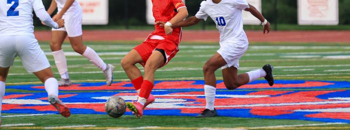 Horizontal view of many soccer players fighting for the soccer ball during a game.