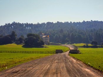 Road amidst field against clear sky