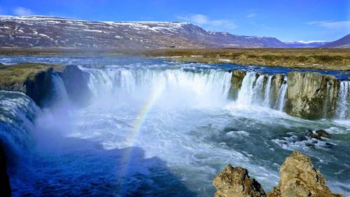 Scenic view of waterfall against sky