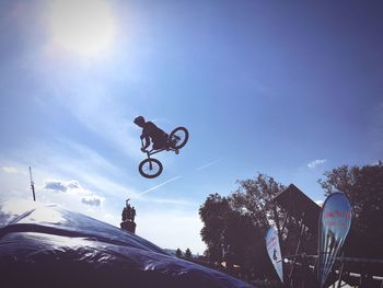 Low angle view of man jumping against sky