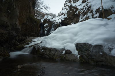 Scenic view of waterfall against sky during winter