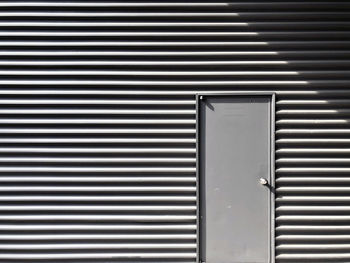 A photo of the striped metal wall and a door on it.