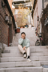 Portrait of young man sitting on staircase in city