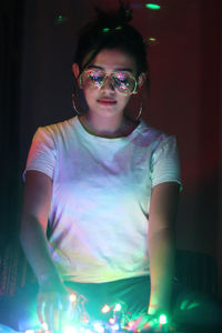 Woman with illuminated lighting equipment in darkroom