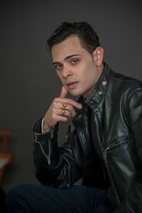 Portrait of young man sitting against gray background