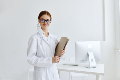 Portrait of smiling young woman standing against wall