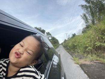 Portrait of smiling woman on road against sky