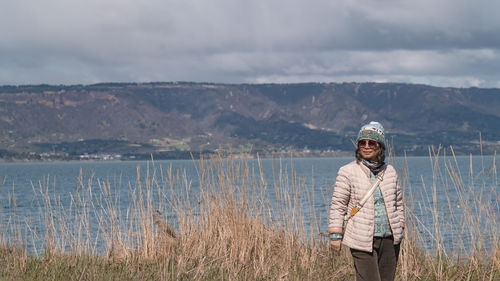 Portrait of young woman standing against lake