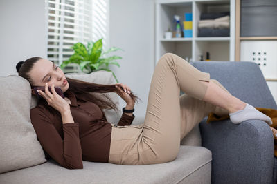 Young woman using laptop while sitting on sofa at home