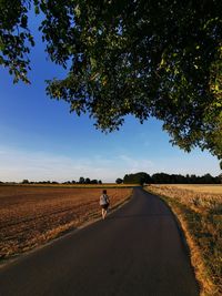 Road amidst field against sky