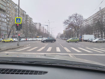 Road sign by city street against sky