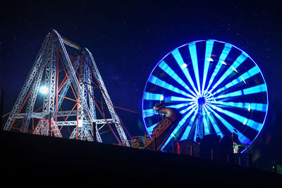 Low angle view of illuminated ferris wheel against sky at night