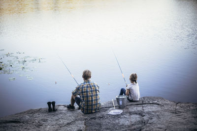 Rear view of father and daughter fishing at lake