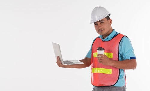 Man holding mobile phone while standing against white background