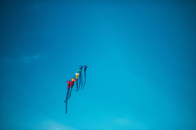 Low angle view of kites flying against clear sky