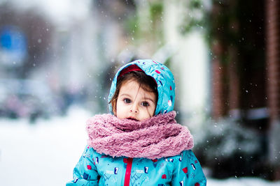 Portrait of cute girl in warm clothing during snowfall