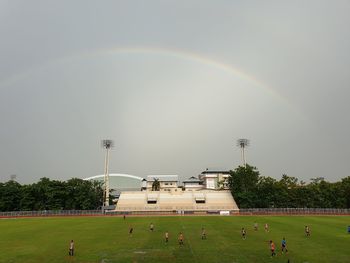People on field against rainbow in sky