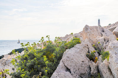 Scenic view of rocks by sea against sky