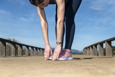 Close up of a sporty woman touching her toes, warm up exercises outside.