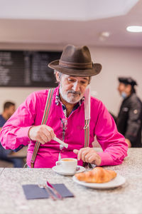 Senior man eating breakfast at cafe