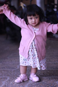 Full length of cute girl standing on pink umbrella