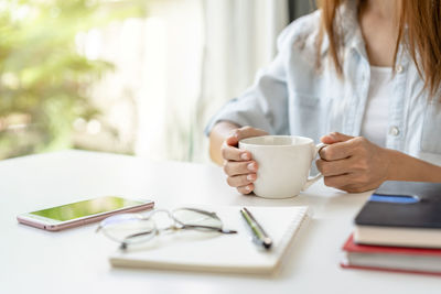 Woman holding coffee cup on table