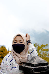 Portrait of young woman standing against clear sky