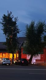 Cars on street by buildings against sky at dusk